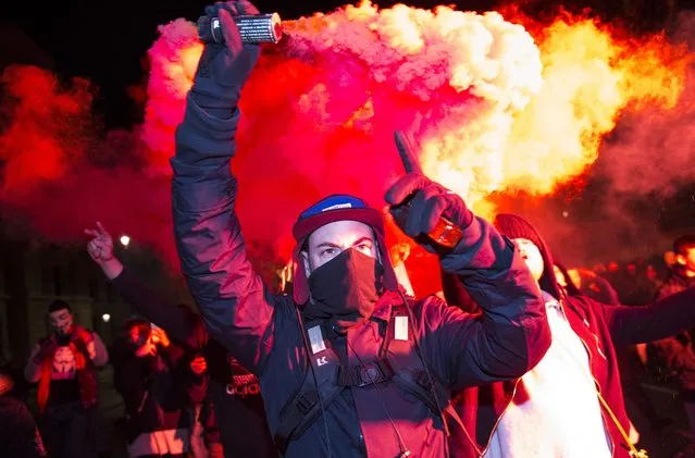 A masked protester holds up a flare on Whitehall during the Million Mask March on November 5, 2016 in London, England. Thousands of demonstrators, many wearing the Guy Fawkes mask associated with the Anonymous hacking collective, take part in the annual Million Mask March through the streets of central London today. The anti-establishment demonstration, which falls on Guy Fawkes Night, is one of several taking place in cities around the world. (Photo by Jack Taylor/Getty Images)