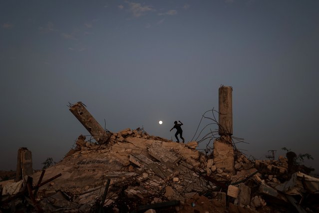 A youth plays on the rubble of a destroyed building as the Cold Moon, the last supermoon of the year, rises over the Nuseirat camp for displaced Palestinians in the central Gaza Strip on December 4, 2025. The United States, alongside Qatar and Egypt, secured a truce in Gaza that came into effect on October 10 and has mostly halted two years of war between Israel and Palestinian militant group Hamas. (Photo by Eyad Baba/AFP Photo)
