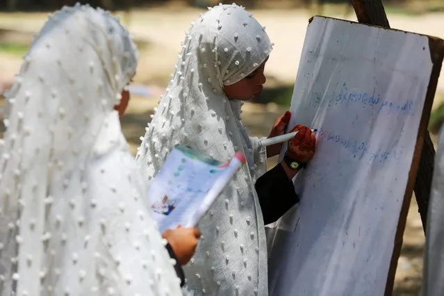 Afghan school girls attend a class at an open air primary school in Jalalabad on May 7, 2023. (Photo by Shafiullah Kakar/AFP Photo)
