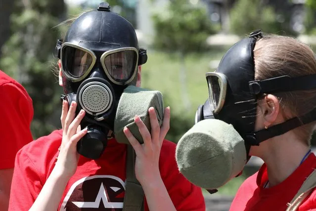Members of Russia's Youth Army military-patriotic movement wear gas masks during a demonstration lesson that is part of an extracurricular educational program, which involves weapon training, first aid treatment, camping skills and other courses, in Sevastopol, Crimea on May 19, 2023. (Photo by Alexey Pavlishak/Reuters)