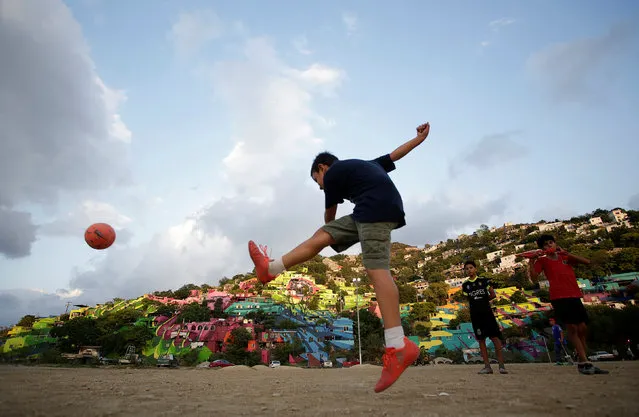 A young boy kicks a ball in front of multicoloured houses on the hillside in Cerro de la Campana, Monterrey, Mexico on June 4, 2018. (Photo by Daniel Becerril/Reuters)