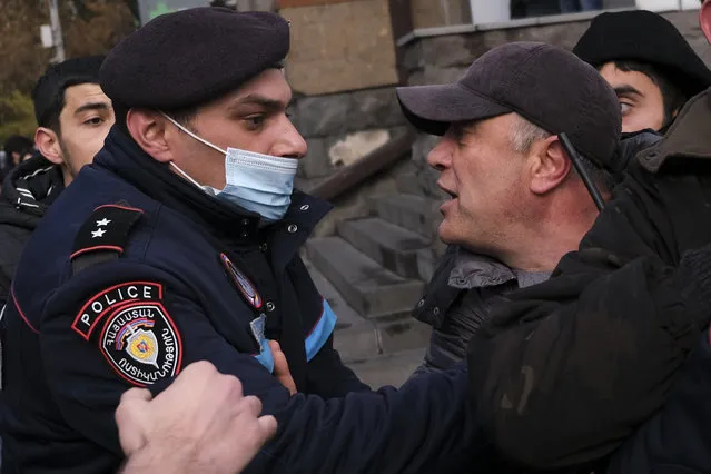 A police officer tries to detain demonstrators during a rally demanding the resignation of the country's prime minister over his handling of the conflict with Azerbaijan over Nagorno-Karabakh in Yerevan, Armenia, Tuesday, December 8, 2020. Armenian opposition politicians and their supporters have been calling for Prime Minister Nikol Pashinyan to step down ever since he signed a peace deal that halted 44 days of deadly fighting over the separatist region, but called for territorial concessions to Azerbaijan. (Photo by Hrant Khachatryan/AP Photo)