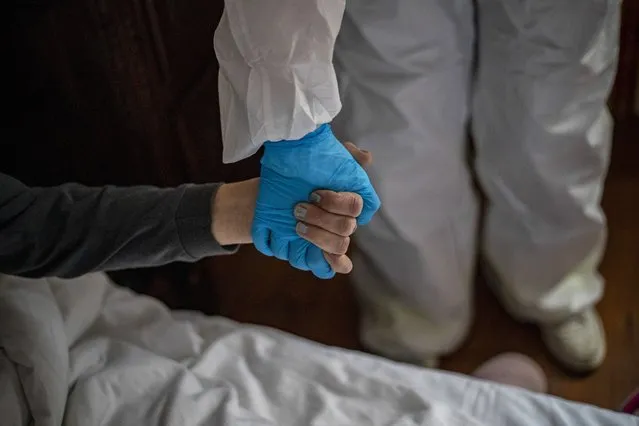 A healthcare worker wearing personal protective equipment (PPE) holds a hand of a homeless woman during taking a swab sample in a hotel in Prague, Czech Republic, 01 March 2021 (issued 02 March 2021). Lockdown and measures against COVID-19 disease caused by the SARS-CoV-2 coronavirus led to the temporary closure of hotels in the Czech Republic. Councilors in Prague, the capital of the country with one of the largest infection rates in the EU, took the opportunity to rent these tourist place and accommodate homeless people who tested positive for coronavirus. The City of Prague in cooperation with the Center of Social Services of Prague, opened the first 'Covid house' in a 4-star hotel in November 2020. Currently there are three facilities in Prague with a capacity for 181 people. According to the Czech Ministry of Labour and Social Affairs, it is estimated that there are about 3,250 homeless people in Prague, and the incidence of COVID-19 disease among them is increasing. (Photo by Martin Divisek/EPA/EFE)