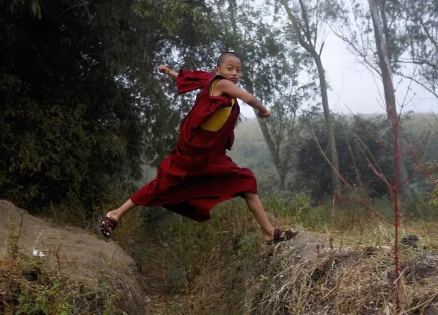 A young Buddhist monk jumps to cross a drain as he arrives to attend the Jangchup Lamrim teachings conducted by the Tibetan spiritual leader the Dalai Lama (unseen) at the Tashi Lhunpo Monastery in Bylakuppe in the southern state of Karnataka, India, December 21, 2015. (Photo by Abhishek N. Chinnappa/Reuters)