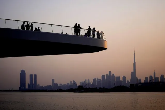 People stand on the observation deck of the Dubai Creek Harbour in Dubai, United Arab Emirates, Sunday, June 18, 2023, to view the city skyline with the world's tallest tower, the Burj Khalifa. (Photo by Kamran Jebreili/AP Photo)