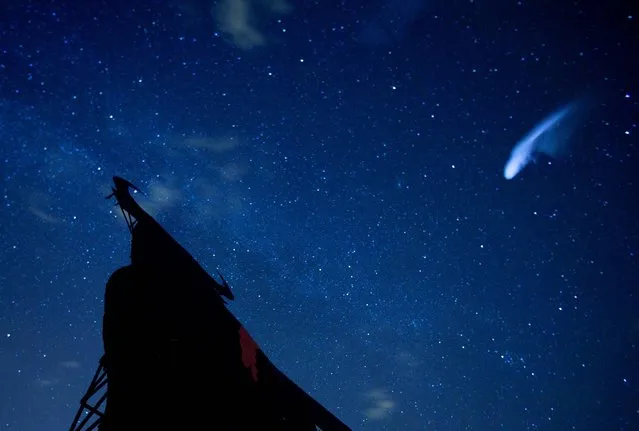In this long exposure photo, a streak appears in the sky during the annual Perseid meteor shower above a roadside silhouette of a Spanish fighting bull, conceived decades ago in Spain as highway billboards, in Villarejo de Salvanes, central Spain in the early hours of Monday August 12, 2013. (Photo by Paul White/AP Photo)