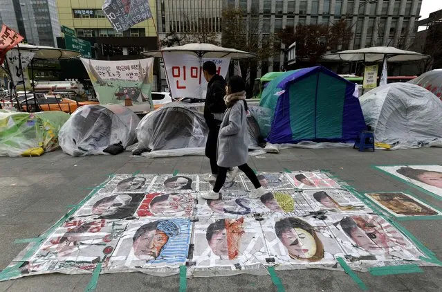 A couple walks on paintings criticizing South Korean President Park Geun-hye on a street in Seoul, South Korea, Wednesday, November 23, 2016. Park's office on Wednesday confirmed revelations by an opposition lawmaker that it purchased about 360 erectile dysfunction Viagra pills and the generic version of the drug in December. (Photo by Ahn Young-joon/AP Photo)