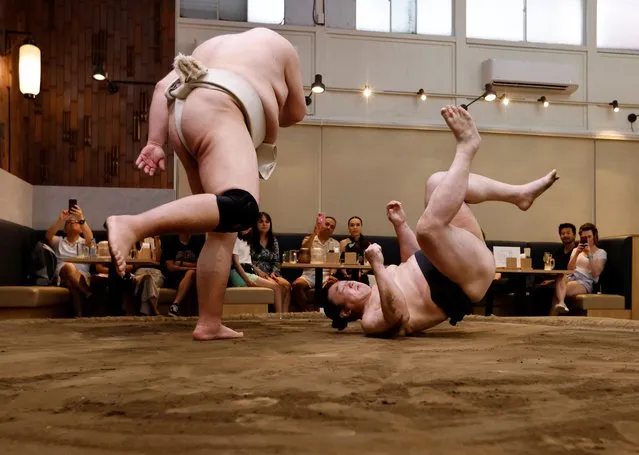 Former sumo wrestlers Kotoohtori, 40, and Towanoyama, 45, engage in sparring before tourists from abroad, on the sumo ring at Yokozuna Tonkatsu Dosukoi Tanaka in Tokyo, Japan on June 30, 2023. (Photo by Issei Kato/Reuters)