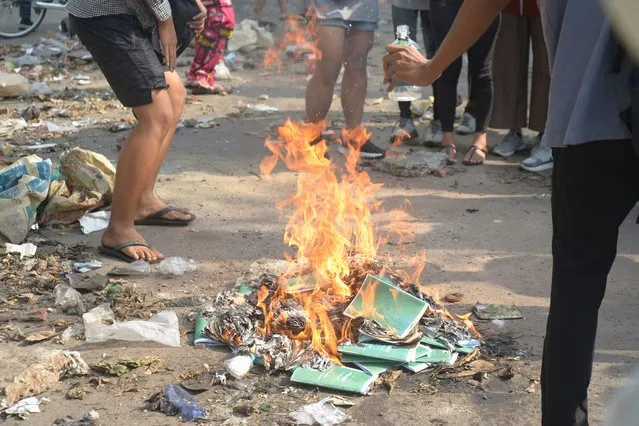 Anti-coup protesters burn constitution books at Tarmwe township in Yangon, Myanmar on Thursday April 1, 2021. Opponents of Myanmar‚ military government declared the country‚ 2008 constitution void and put forward an interim replacement charter late Wednesday in a major political challenge to the ruling junta. (Photo by AP Photo/Stringer)