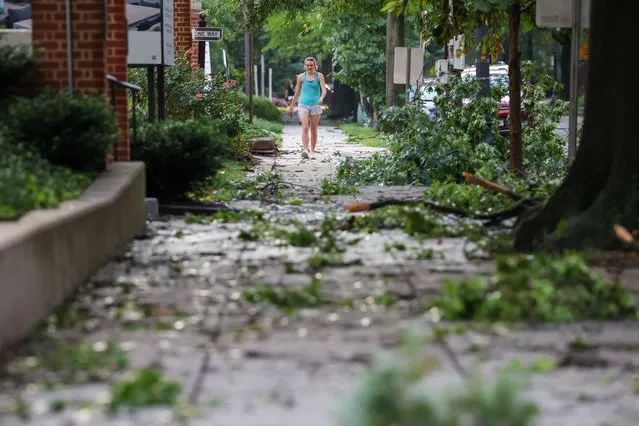 A person walks through downed branches following a brief storm in Washington, D.C. on July 29, 2023. (Amanda Andrade-Rhoades/For The Washington Post)