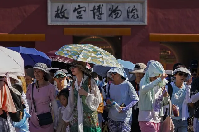 Visitors wear sun hats and carry umbrellas as they leave the Forbidden City on a hot day in Beijing, Thursday, June 29, 2023. (Photo by Andy Wong/AP Photo)