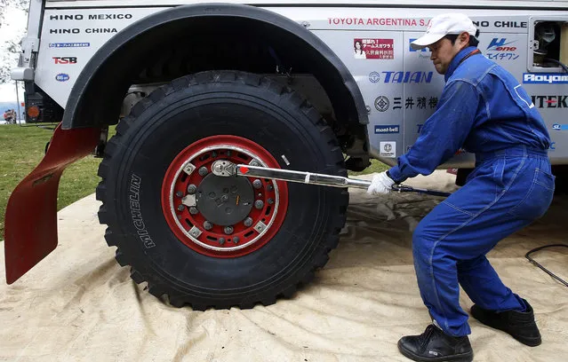 A mechanic tightening the nuts of a truck that is part of the Rally Dakar 2016 in Villa Carlos Paz, Argentina, on 3 January 2016 after the suspension of the first stage of the Rally Dakar 2016, because of heavy rains and thunder storms in the region. (Photo by Felipe Trueba/EPA)