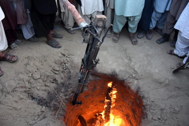 A Kalashnikov is thrown in a fire as a symbol to end enmities among different tribes in Balochistan province during a Tribal Jirga (meeting) in Qila Abdullah, Pakistan, 10 September 2018. Hundreds of Tribal elders from different Tribes of Balochistan gathered in Qila Abdullah to find ways to reduce tensions among different tribes and to end decades long enmities and feuds among different tribes that has claimed thousands of lives in last many years. (Photo by Jamal Taraqai/EPA/EFE)