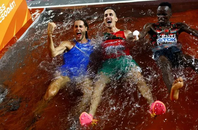 (L to R) Men's high jump gold medalist Gianmarco Tamberi of Team Italy, Men's 3000m Steeplechase gold medalist Soufiane El Bakkali of Team Morocco and bronze medalist Abraham Kibiwot of Team Kenya jump into the water on track during day four of the World Athletics Championships Budapest 2023 at National Athletics Centre on August 22, 2023 in Budapest, Hungary. (Photo by Kai Pfaffenbach/Reuters)