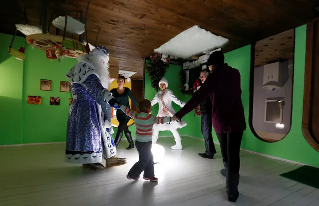 Visitors take part in a performance with employees dressed as Ded Moroz, the Russian equivalent of Santa Claus, and his granddaughter Snegurochka (Snow Maiden), inside an upside down house, constructed as an attraction for local residents and tourists and located at the Royev Ruchey Park of Flora and Fauna in the suburbs of Krasnoyarsk, Russia, December 7, 2016. (Photo by Ilya Naymushin/Reuters)