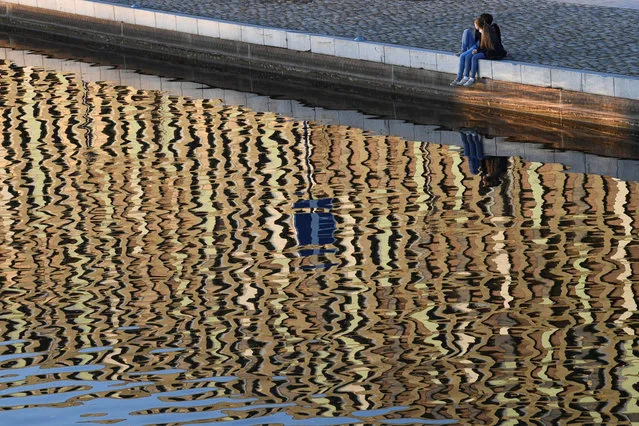 People are seen on the bank of Spree river in the setting sun, amid the coronavirus disease (COVID-19) pandemic, in Berlin, Germany, March 2, 2021. (Photo by Annegret Hilse/Reuters)