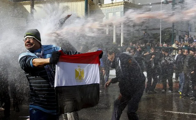 A protester holds an Egyptian flag as he stands in front of water cannons during clashes in Cairo January 28, 2011. (Photo by Yannis Behrakis/Reuters)