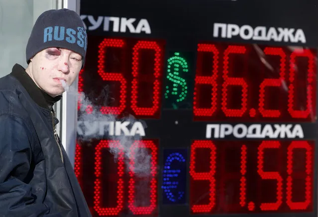 A man smokes near a board showing currency exchange rates of the U.S. dollar and euro against the rouble in Moscow, Russia, January 21, 2016. Russia's rouble fell further on January 20, setting a new record low of over 81 roubles per dollar as a bearish mood gripped Russian financial markets. (Photo by Sergei Karpukhin/Reuters)