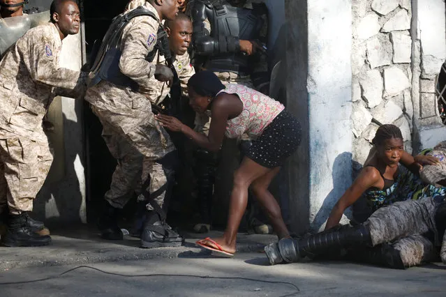 A woman takes cover between Haitian National Police officers during a shooting after a ceremony for the anniversary of the killing of Jean-Jacques Dessalines in Port-au-Prince, Haiti on October 17, 2018. (Photo by Andres Martinez Casares/Reuters)