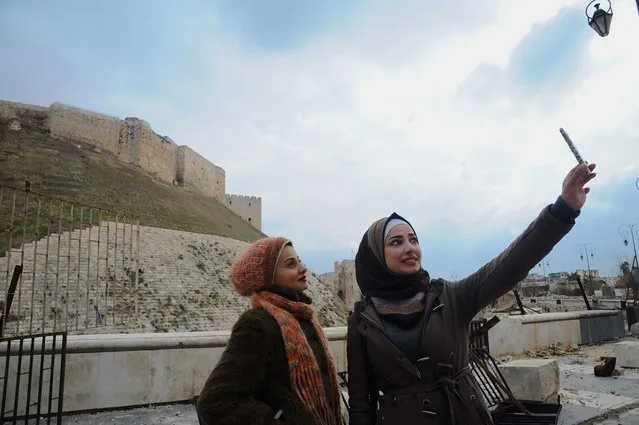 Women take a selfie outside Aleppo's historic citadel, in the government controlled area of the city, Syria December 17, 2016. (Photo by ZUMA Press/Alamy Stock Photo)