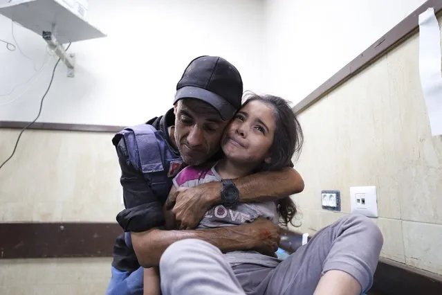 A Palestinian journalist comforts his niece wounded in an Israeli strike on her family home in Nusseirat refugee camp, in a hospital in Deir el-Balah, Gaza Strip, Sunday, October 22, 2023. (Photo by Ali Mahmoud/AP Photo)