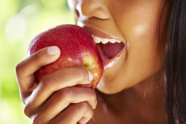 Woman biting red apple, close-up. (Photo by Getty Images/Westend61)