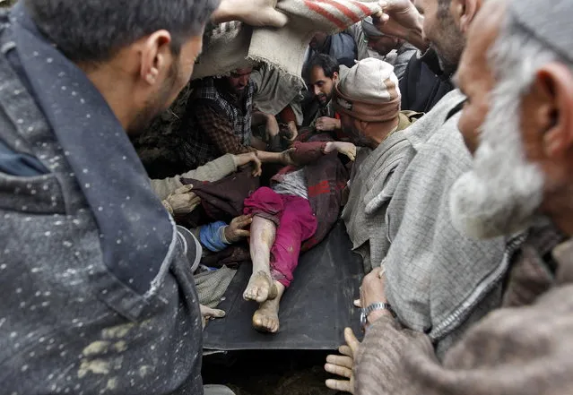 Villagers and rescue workers carry the body of a victim amongst the rubble after a hillside collapsed onto a house at Laden village, west of Srinagar, March 30, 2015. (Photo by Danish Ismail/Reuters)
