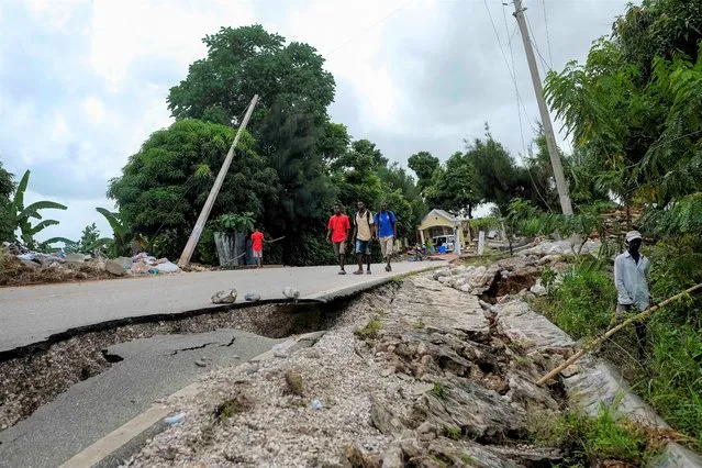Residents walk on a damaged road in Rampe, Haiti, Wednesday, August 18, 2021, four days after 7.2-magnitude earthquake hit the southwestern part of the country. (Photo by Matias Delacroix/AP Photo)