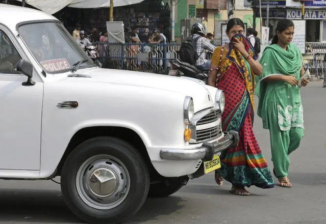An Indian woman covers her face to avoid fumes emitting from passing vehicles as she crosses a busy street in Kolkata, India, Monday, April 6, 2015. Indian Prime Minister Narendra Modi on Monday blamed the changing lifestyles that have come with India's economic development for rising pollution levels that have given the country some of the world's dirtiest air. (Photo by Bikas Das/AP Photo)