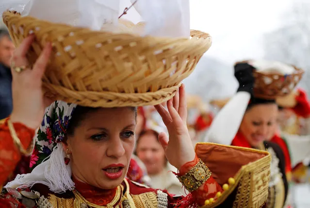 A woman dressed in a traditional folk costume balances a basket of bread on her head during Epiphany day celebration in Bitushe, Macedonia January 19, 2017. (Photo by Ognen Teofilovski/Reuters)