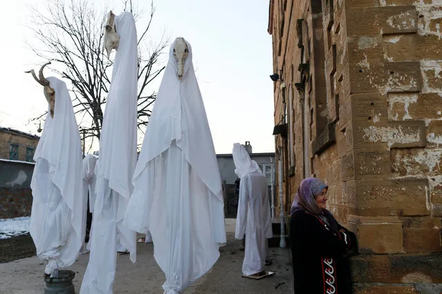 A resident waits near puppets with white sheets in Camlica Village, prior the “Bocuk Festival” in Kesan district of Edirne city, Turkey 21 January 2017. Residents of Camlica Village dress up in white sheets and paint their faces to spook people as ghosts. According to a tradition from the Middle Ages, every year residents participate in a special evening ritual, called as “Bocuk Geces”. Bocuk is a word used in the Thrace region for representing the harshest winter night. (Photo by Sedat Suna/EPA)