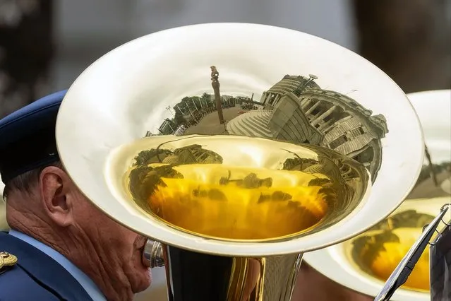 The parliament building is reflected in a tuba played by a military honour guard during the re-starting of Parliament following the October 14 general election, in Wellington on December 6, 2023. (Photo by Marty Melville/AFP Photo)
