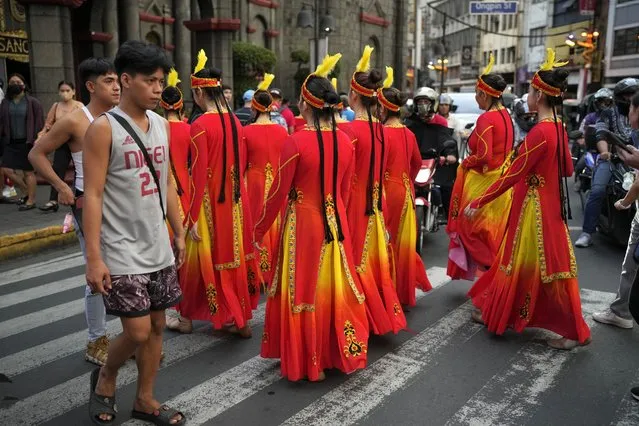 Dancers in costumes cross a street as they participate during the 430th anniversary of Manila's Chinatown, said to be the oldest in the world, at the capital's Binondo district, Philippines on Thursday, February 1, 2024. Crowds are flocking to Manila's Chinatown to usher in the Year of the Wood Dragon and experience lively traditional dances on lantern-lit streets with food, lucky charms and prayers for good fortune. (Photo by Aaron Favila/AP Photo)