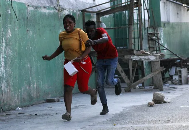People flee as police officers clash with gangs during a protest against Prime Minister Ariel Henry's government and insecurity, in Port-au-Prince, Haiti on March 1, 2024. (Photo by Ralph Tedy Erol/Reuters)