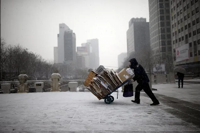 A man carries scraps in a handcart during snowfall in central Seoul, South Korea, February 16, 2016. (Photo by Kim Hong-Ji/Reuters)