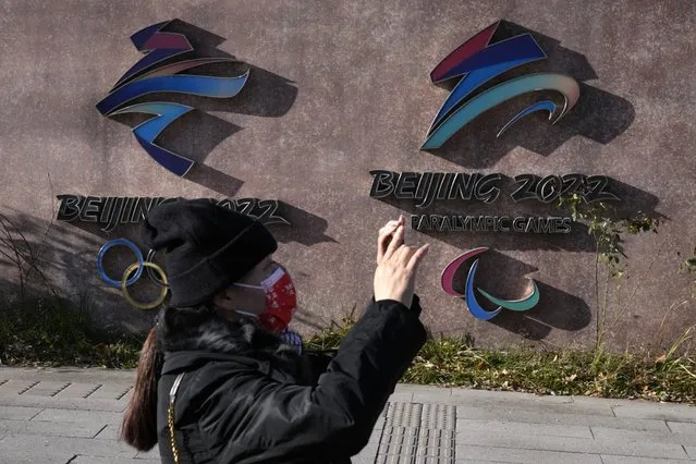 A woman wearing takes photos near the logos for the Beijing Winter Olympics and Paralympics in Beijing, China, Tuesday, November 9, 2021. China on Tuesday, Dec. 7, 2021 accused the United States of violating the Olympic spirit by announcing an American diplomatic boycott of February's Beijing Winter Games. (Photo by Ng Han Guan/AP Photo)