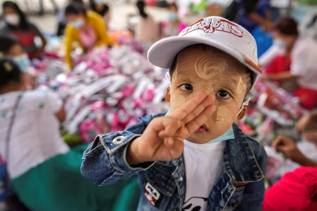A boy from Myanmar, who lives in Thailand, flashes a three-finger salute at a temporary donation station for sending relief supplies to refugees who fled a flare-up in fighting between the Myanmar army and ethnic minority rebels in Mae Sot district, Tak province, Thailand, December 18, 2021. (Photo by Athit Perawongmetha/Reuters)