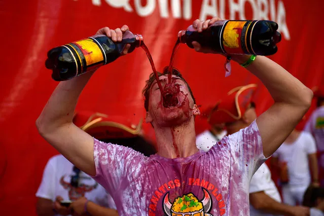 Revellers drink wine as they start celebrating early while waiting for the launch of the “Chupinazo” rocket, to celebrate the official opening of the 2019 San Fermin fiestas with daily bull runs, bullfights, music and dancing in Pamplona, Spain, Saturday July 6, 2019. (Photo by Alvaro Barrientos/AP Photo)