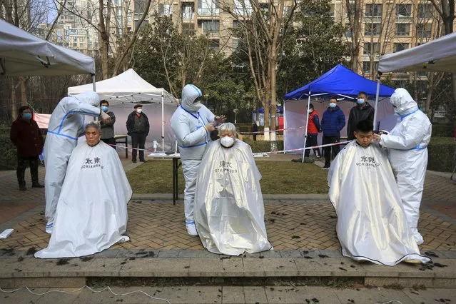 Hairdressers wearing protected suits cut residents' hair at a residential block which has become under lockdown in Xi'an in northwest China's Shaanxi province on Sunday, January 9, 2022. A major Chinese city near Beijing has placed its 14 million residents on partial lockdown after a number of children and adults tested positive for COVID-19, including at least two with the omicron variant. Elsewhere, millions of people are being confined to their homes in Xi'an and Yuzhou, two cities that are farther away but have larger outbreaks traced to the delta variant. (Photo by Chinatopix via AP Photo)
