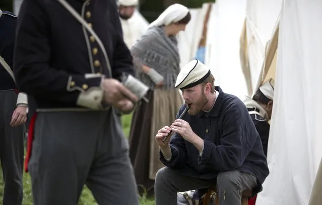 In this May 9, 2015, photo, an historical re-enactor dressed as a soldier of the Belgian-Dutch 7th Battalion of the Line plays the flute at a Napoleonic era living history camp in Elewijt, Belgium. The Belgian-Dutch living history group is coordinating their group for participation in the 200th anniversary of the Battle of Waterloo which will take place in June 2015. (AP Photo/Virginia Mayo)