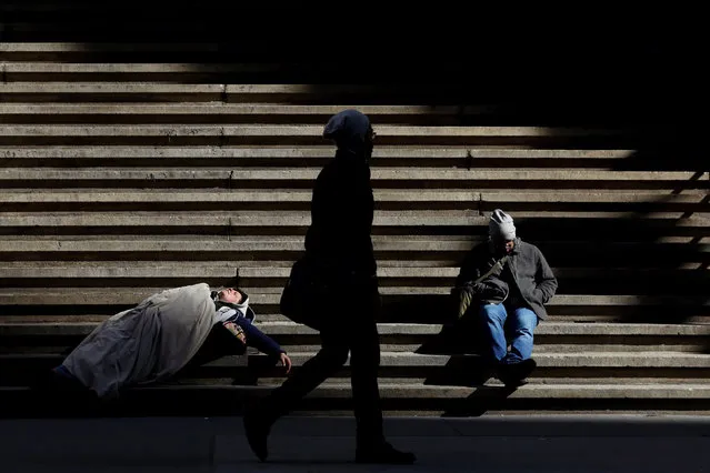 A homeless person (L) sleeps on the steps of Federal Hall on Wall St. in New York City, U.S., February 28, 2017. (Photo by Brendan McDermid/Reuters)