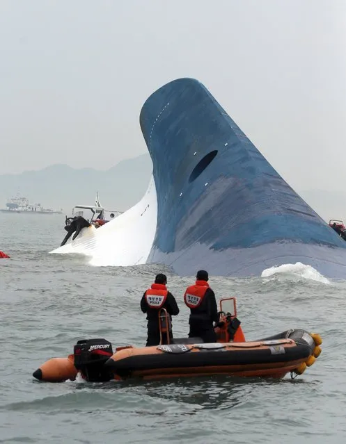 South Korean coast guard officers watch on as the ferry Sewol sinks in the water off of the country's southern coast, April 16, 2014. (Photo by Hyung Min-woo/AP Photo/Yonhap)