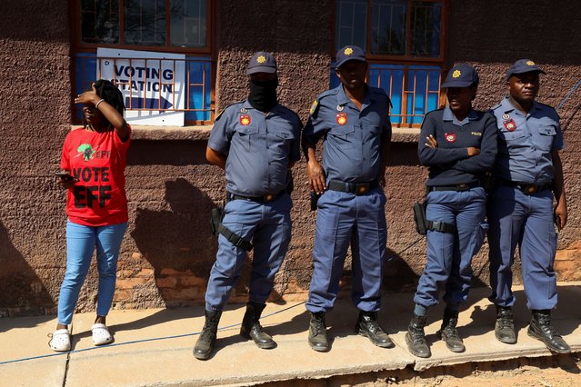 A woman stands next to police on the day of the South African elections in Seshego, Limpopo Province, South Africa on May 29, 2024. (Photo by Alet Pretorius/Reuters)