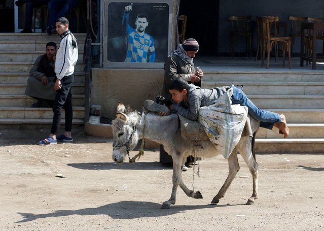 An Egyptian boy rides his donkey in front of a cafeteria with a picture of former Barcelona's forward player Lionel Messi at a village, near Giza, on the outskirts of Cairo, Egypt, February 7, 2022. (Photo by Amr Abdallah Dalsh/Reuters)