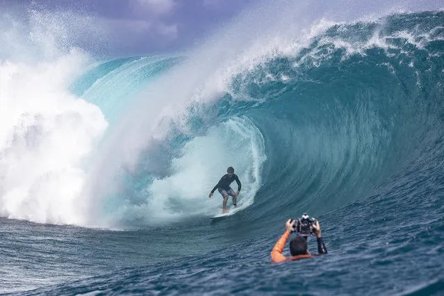 Us surfer Benji Brand from Hawaii practices next to a photographer taking pictures ahead of the Tahiti pro surfing trial at the famous break Teahupoo in Tahiti, French Polynesia on August 18, 2019. (Photo by Brian Bielmann/AFP Photo)