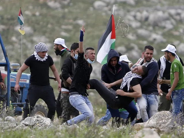 Palestinians carry injured demonstrator during clashes with Israeli forces following a protest to mark the Land Day near the village of Madama, south of the West Bank city of Nablus, Thursday, March 30, 2017. Land Day commemorates the killing of six Arab citizens of Israel by the Israeli army and police on March 30, 1976 during protests over Israeli confiscations of Arab land. (Photo by Majdi Mohammed/AP Photo)