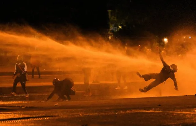 A demonstrator falls as they are hit by water cannon during clashes with riot police amid ongoing protests against the government of Colombian President Ivan Duque in Bogota on June 12, 2021. Dozens of people have been killed in protests that erupted around the country on April 28, initially against a tax hike that would have mostly affected the middle classes, but which have morphed into a major anti-government movement. (Photo by Juan Barreto/AFP Photo)
