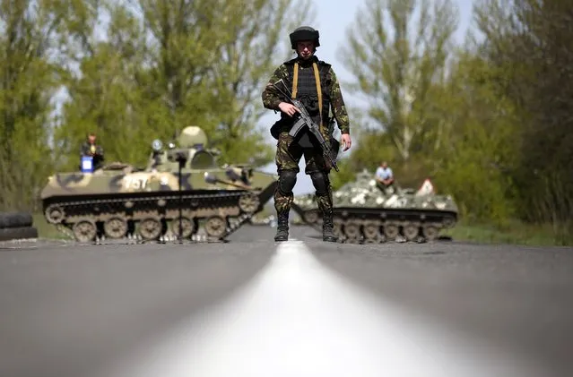 A Ukrainian soldier stand guard in front of armoured personnel carriers at a check point near the village of Malinivka, south-east of Slaviansk, in eastern Ukraine April 27, 2014. The de facto mayor of the Ukrainian city of Slaviansk said on Sunday mediators from the Organisation for Security and Cooperation in Europe who are seeking the release of a group of detained observers had arrived in the city. (Photo by Marko Djurica/Reuters)