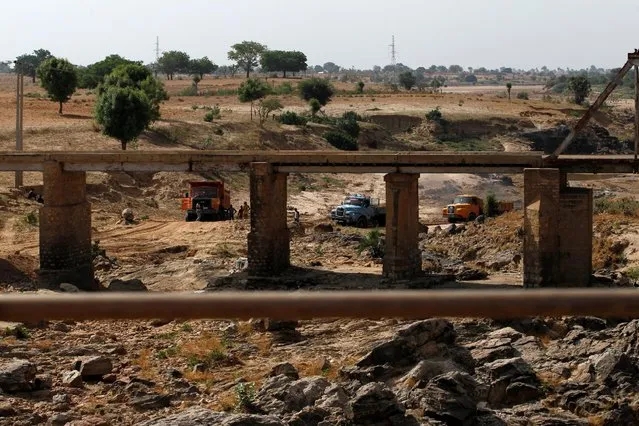 Trucks are loaded with sand from a dry river bed behind a disused bridge in Zamfara, Nigeria April 21, 2016. (Photo by Afolabi Sotunde/Reuters)