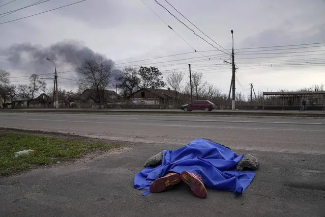 The dead body of a person lies covered in the street in Mariupol, Ukraine, Monday, March 7, 2022. (Photo by Evgeniy Maloletka/AP Photo)